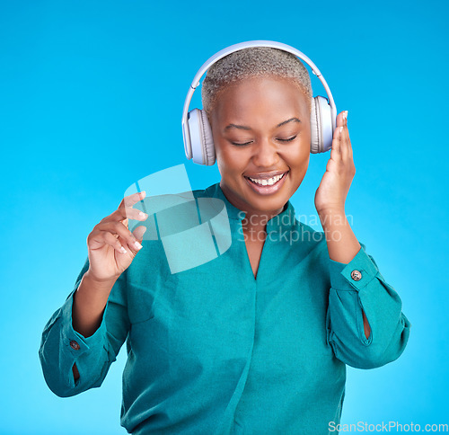 Image of African woman, headphones and studio for listening, music and smile with dancing by blue background. Young gen z student, sound tech and happy for audio streaming, online radio and excited with dance