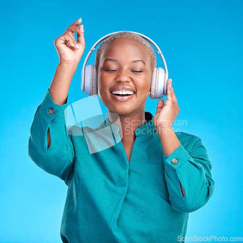 Image of African woman, headphones and studio for dancing, music or listen with smile by blue background. Young gen z student, sound tech and happy for audio streaming subscription, radio or excited for dance