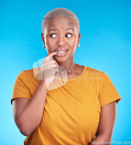 Image of Black woman, biting nails and anxiety in studio with thinking, confused or ideas for decision by blue background. African girl, stress and finger in mouth for fear, scared or brainstorming for choice