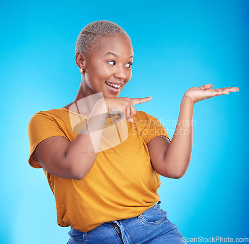 Image of Decision, pointing and black woman with a smile, presentation and advertising on a blue studio background. Sales, female person or model with discount deal, sales and choice with promotion or showing