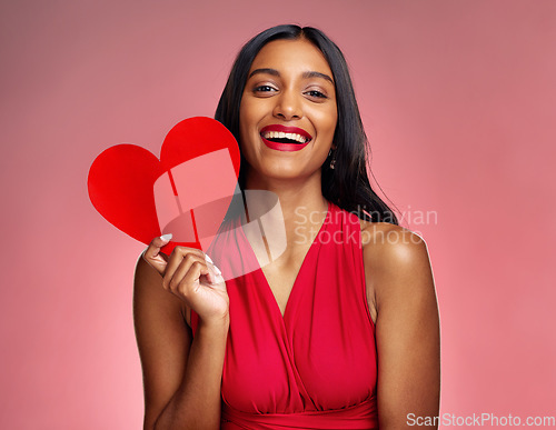 Image of Portrait, heart and social media with a woman on a pink background in studio for love or romance. Smile, emoji and valentines day with a happy young female holding a shape or symbol of affection