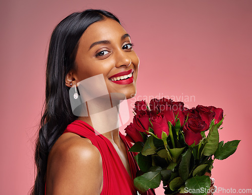 Image of Happy, beauty and portrait of a woman with a rose on a studio background for valentines day. Makeup, model and face of a young Indian girl with a flower bouquet for romance or love on pink backdrop