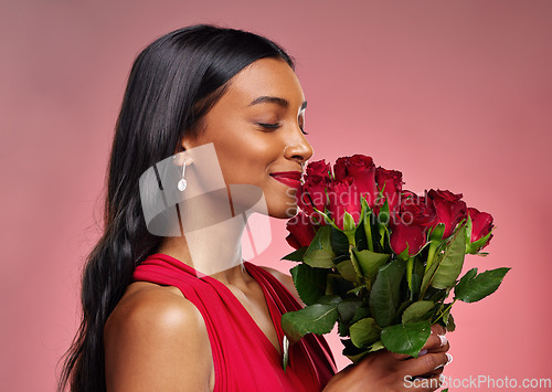 Image of Face, beauty and a woman smelling a roses on a studio background for valentines day. Makeup, model and happy young Indian girl profile with a flower bouquet for romance or love on pink backdrop