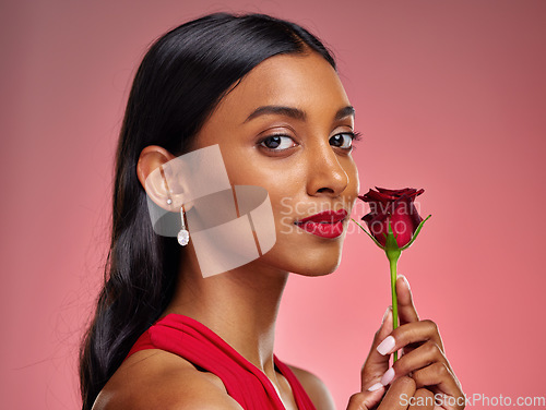 Image of Beautiful, portrait and an Indian woman with a rose on a studio background for valentines day. Serious, model and face of a young girl with a flower for romance or love isolated on a backdrop