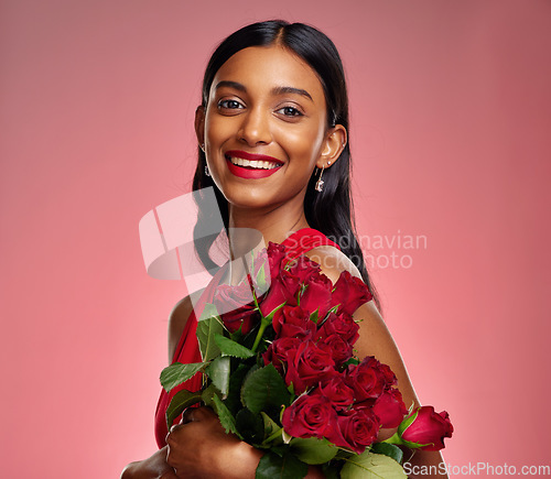 Image of Happy, flowers and portrait of an Indian woman on a studio background for valentines day. Smile, beautiful and a young model or girl with a floral bouquet on a backdrop for luxury present of roses