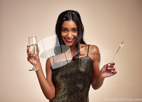 Image of Portrait, woman and sparkler for celebration with Champagne, New Years party and fun on studio background. Fireworks, alcohol drink in glass and holiday, event and happy female person with sparks