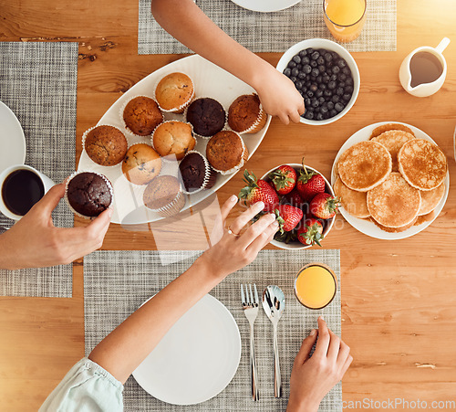 Image of Breakfast, food and hungry people in dining room, eating healthy and above table setting or home in the morning. Fruit, pancakes and hands on strawberry or muffin plate for nutrition or diet