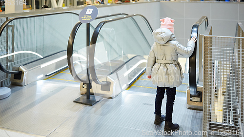 Image of Back view of child going on escalator background. Shopping mall, airport travel, love care, protection concept