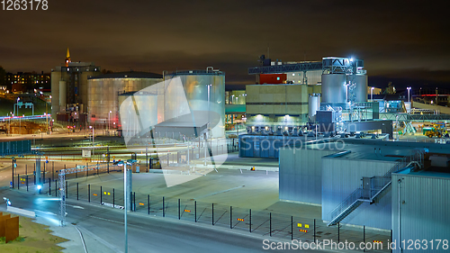 Image of Modern grain terminal at night. Metal tanks of elevator. Grain-drying complex construction. Commercial grain or seed silos at seaport. Steel storage for agricultural harvest