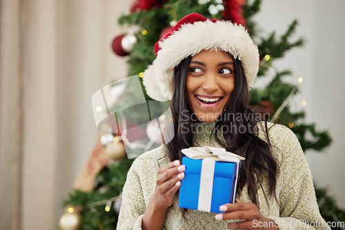 Image of Christmas, thinking or happy woman with a gift or box in present on a holiday celebration at home. Wonder, smile or excited Indian girl with present with giveaway prize package in a house in winter