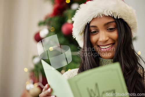 Image of Happy woman reading Christmas card, note or message in home living room in winter holiday celebration. Smile, festive or Indian girl with emotional xmas greeting letter, wishes or kind gift in house