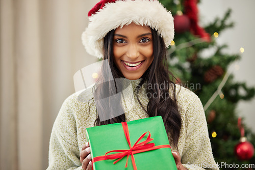 Image of Christmas, portrait or happy woman with a gift box or present on a holiday celebration at home. Face, smile or excited Indian girl with special product or giveaway prize package in a house in winter