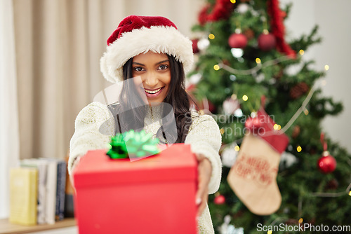 Image of Woman giving gift, Christmas and smile in portrait, celebrate holiday with happiness and wrapped box with ribbon. Special event, female person at home with present and package, festive and xmas