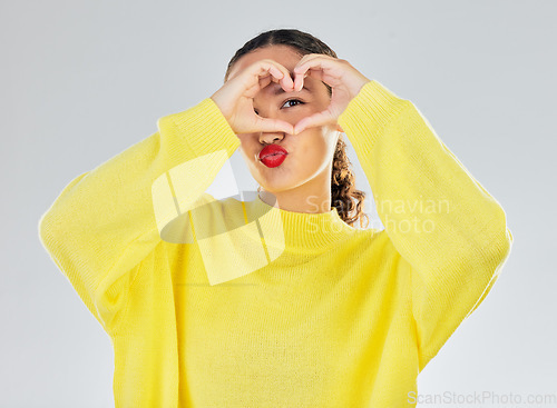 Image of Woman, portrait and heart hands for love, care or romance in casual fashion against a white studio background. Female person with hand in support emoji, sign and symbol for health or wellness