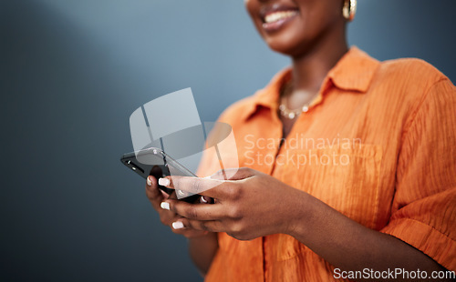 Image of Typing, happy and hands with a phone on a dark background for communication or social media. Smile, contact and a black woman with a mobile for an app or chat isolated on a studio backdrop for web