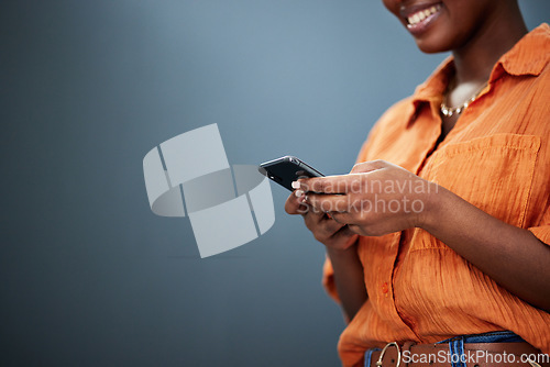 Image of Typing, mockup and hands with a phone on a dark background for communication or social media. Smile, space and a black woman with a mobile for an app or chat isolated on a studio backdrop for web