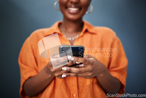 Image of Typing, closeup and hands with a phone on a dark background for communication or social media. Smile, contact and a black woman with a mobile for an app or chat isolated on a studio backdrop for web