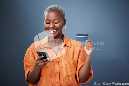 Image of Smile, phone and credit card with a black woman online shopping in studio on a gray background. Mobile, ecommerce and finance payment with a happy young female shopper searching for a deal or sale