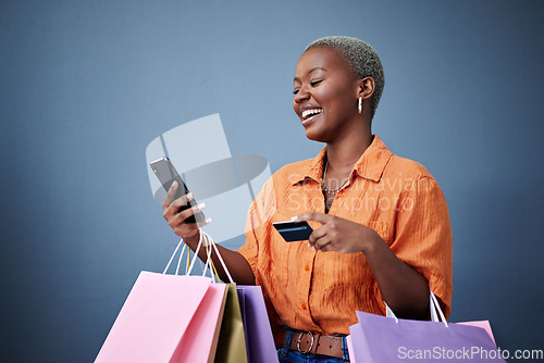 Image of Bags, shopping and black woman with a credit card, cellphone and ecommerce on a grey studio background. Female person, shopper or model with smartphone, boutique items or payment with retail or smile