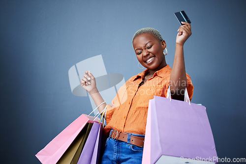 Image of Bags, excited and black woman with a credit card, shopping and boutique items on a grey studio background. Female person, shopper or model with celebration, payment and smile with sales and luxury