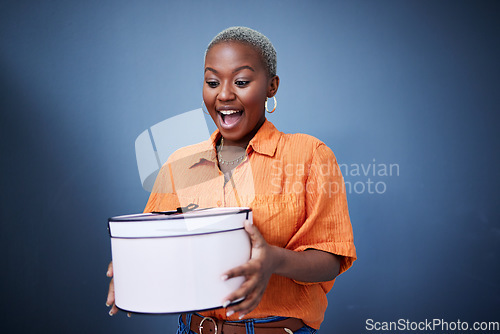 Image of Black woman, present package and surprise in studio with excited smile, birthday and blue background. African girl, happy and wow with box, gift and fashion for celebration, winner and birthday party