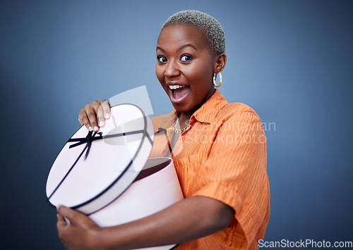 Image of African woman, open present or box in studio portrait with excited smile, surprise and blue background. Girl, happy and wow with package, gift and fashion for celebration, winner and birthday party