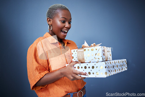 Image of Black woman, gift package and surprise in studio with excited smile, giveaway and blue background. African girl, happy and wow with box, present and fashion for celebration, winner and birthday party