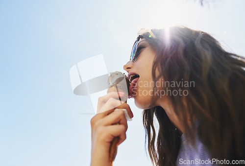 Image of Summer, below and a woman with ice cream on a blue sky for freedom, travel and sweet food. Sun, holiday and a young girl with a dessert during a vacation in spring or a eating gelato and thinking