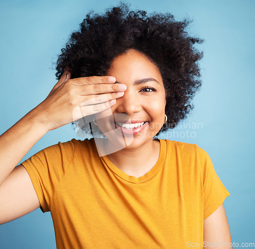 Image of Happy, cover eye and portrait of a woman for comedy, funny and vision check. Smile, confident and a young girl with a hand on face for positivity and a joke isolated on a blue background in studio