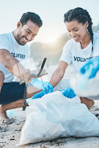 Image of Volunteer, man and woman cleaning beach for world earth day, care and kindness for nature and environment. Help, recycling and happy people at ngo collect plastic waste and pollution from ocean sand.