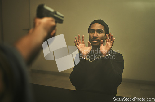 Image of Interrogation, criminal and police with gun in jail for threatening, violence and hostage in station. Arrested, handcuffs and officer with weapon with man with anxiety, worry and scared in prison