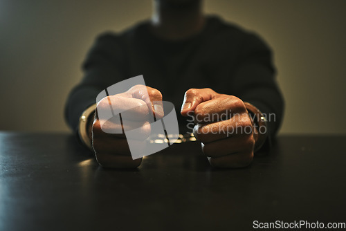 Image of Interrogation, jail and hands of criminal in handcuffs for interview, investigation and arrested in station. Security, law and closeup of man, burglar or thief for crime, stealing and theft in prison