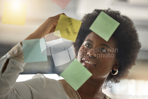 Image of Black woman, writing or entrepreneur brainstorming ideas on glass board with startup strategy in office. Face, sticky notes or businesswoman planning a schedule, timeline or tasks for company growth