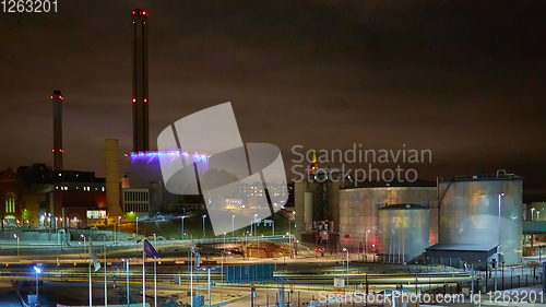 Image of Modern grain terminal at night. Metal tanks of elevator. Grain-drying complex construction. Commercial grain or seed silos at seaport. Steel storage for agricultural harvest