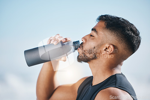 Image of Fitness, man and drinking water outdoors after training, running or morning cardio routine. Thirst, hydration and Indian male runner with bottle drink after sports, workout and body performance