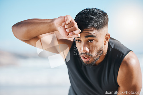 Image of Tired, sweating and fitness break for man outdoor after training, running or cardio workout on blurred background. Sweat, face and Indian male runner with sports fatigue, dehydration from exercise