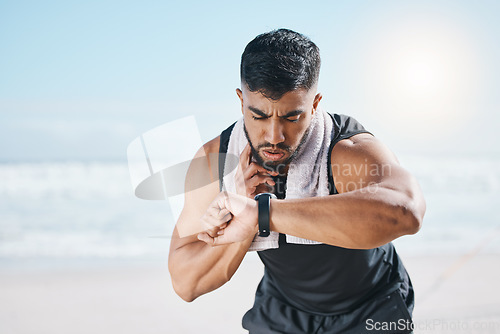 Image of Man, fitness and checking watch for pulse, heart rate or performance on break after workout on the beach. Fit, active and sporty male person with wristwatch for monitoring body exercise by the ocean