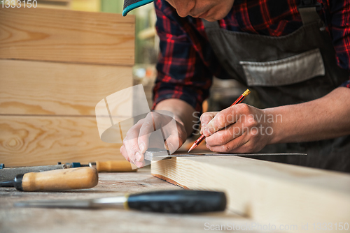 Image of The worker makes measurements of a wooden board