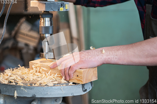 Image of Carpenters with electric drill machine drilling wooden board