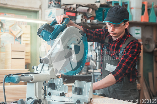 Image of Construction worker cutting wooden board