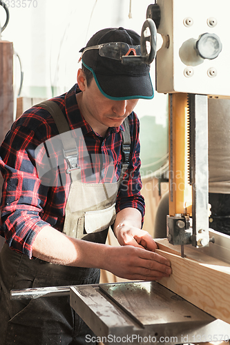 Image of Construction worker cutting wooden board