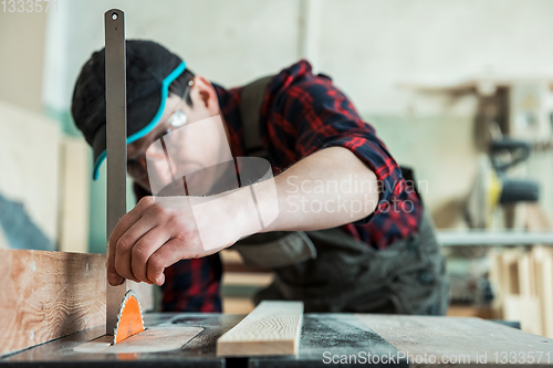 Image of The worker makes measurements of a wooden board