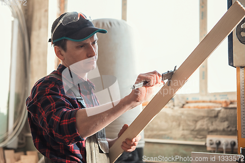 Image of The worker makes measurements of a wooden board