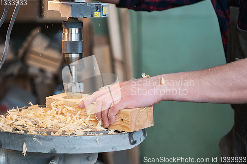 Image of Carpenters with electric drill machine drilling wooden board