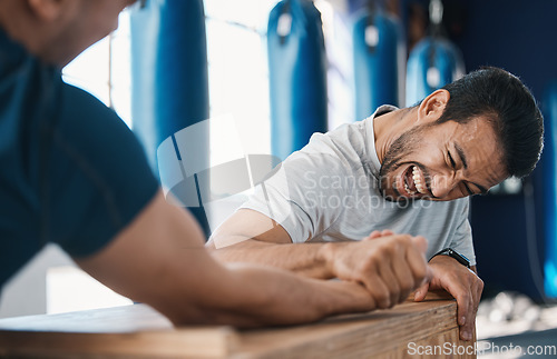 Image of Strength, motivation and men arm wrestling in a gym on a table while being playful for challenge. Rivalry, game and male people or athletes doing strong muscle battle for fun, bonding and friendship.