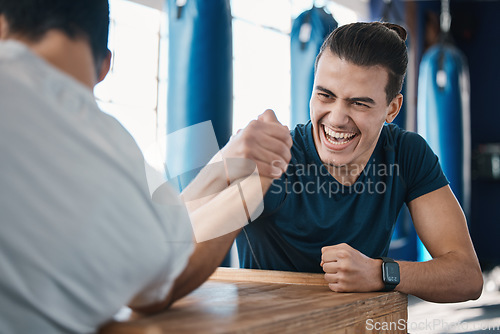 Image of Strong, active and men arm wrestling in the gym on a table while being playful for a challenge. Rivalry, game and male people or athletes doing strength muscle battle for fun, bonding and friendship.