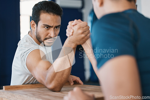 Image of Strength, motivation and male people arm wrestling on a table while being playful for a challenge. Rivalry, game and men athletes doing strength muscles battle for fun, bonding and friendship in gym.