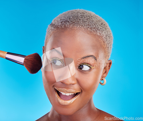 Image of Black woman, face and brush of makeup in studio for application of foundation on blue background. Happy female model, wow and brushing beauty powder on skin with cosmetic tools for facial aesthetic
