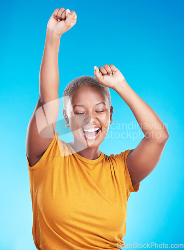 Image of Winner, dance and happy woman on studio, blue background for excited celebration, energy and success. Winning, yes and young, african person dancing with wow, fist and power, goals or cheers in music