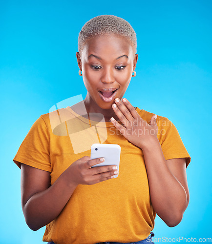 Image of Studio, phone and black woman surprise over reading announcement, winner notification or online sales news. Discount promotion, smartphone information and shocked African person on blue background